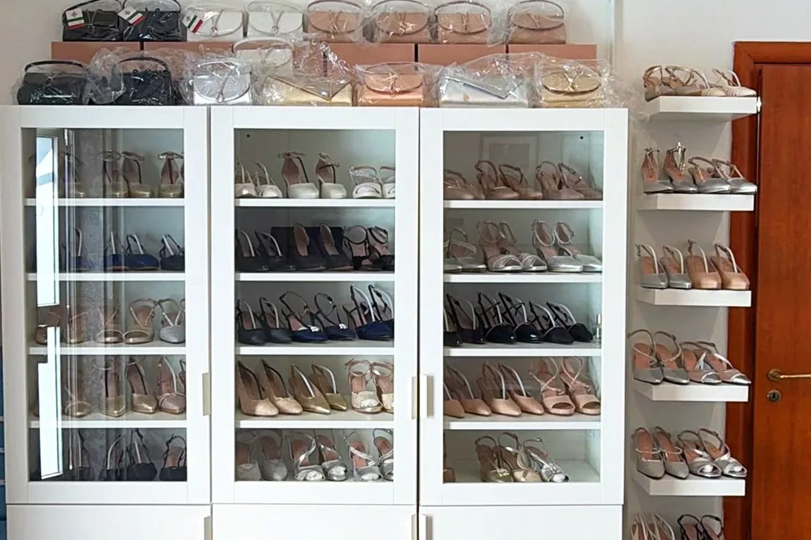 Il campionario di Atelier Due Emme a Trani: tre vetrine di scarpe da sposa e da cerimonia, con le pochette sopra e una colonna di mensole