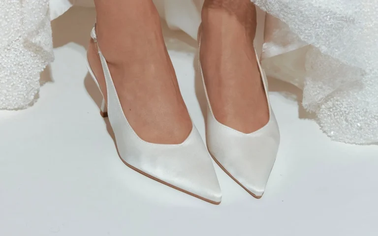 Scarpe da sposa che spuntano dall'orlo di un abito ricamato