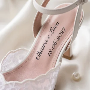 Première rose de l'escarpin de mariée Neve Sposa en dentelle blanche avec les prénoms Chiara et Luca et la date 18-06-2027 en italique noir : image de présentation